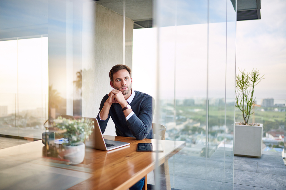 Young entrepreneur thinking up new ideas while working on a laptop at a table at home
