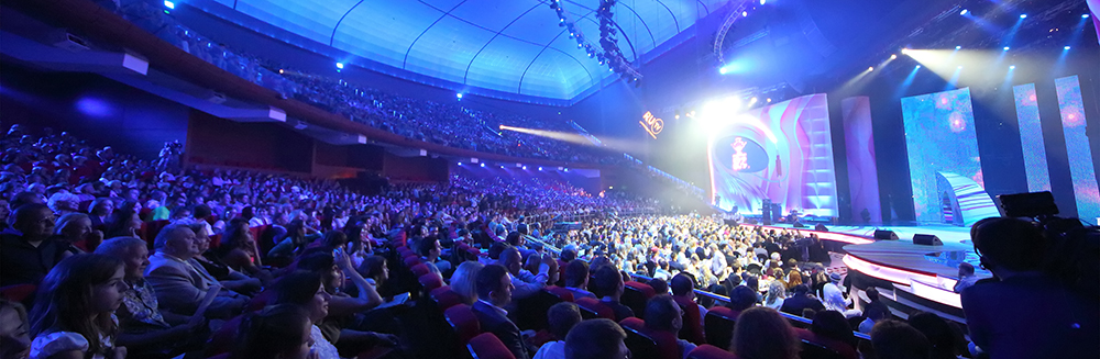 Professional event production setup with stage lighting, cameras, and audience